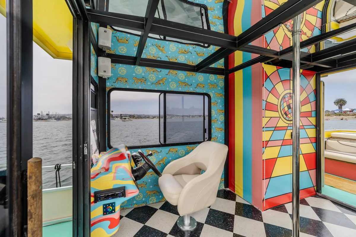 The Disco Boat 1970s interior — psychedelic-swirl helm, leopard-print walls, mirrored ceiling, black-and-white checkerboard floor, fold-down window panels