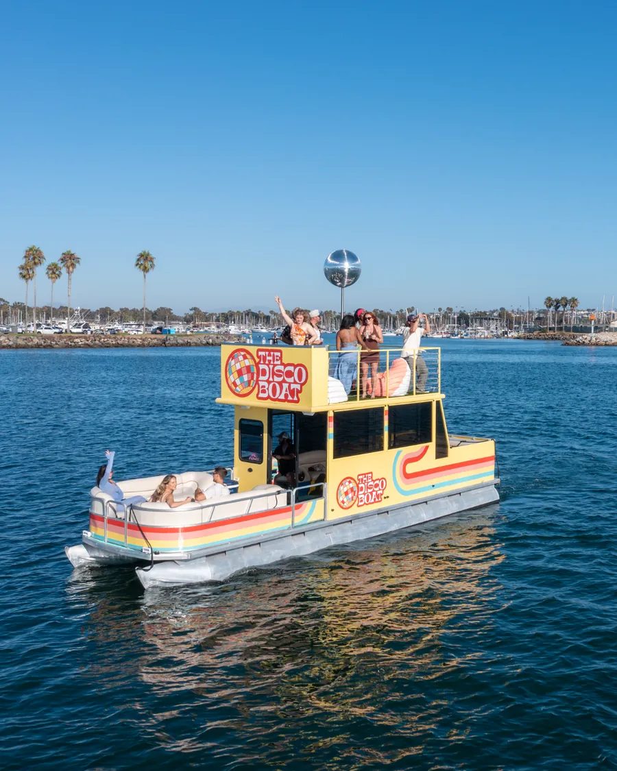 Disco Boat profile against palm trees and golden hour light on San Diego Bay