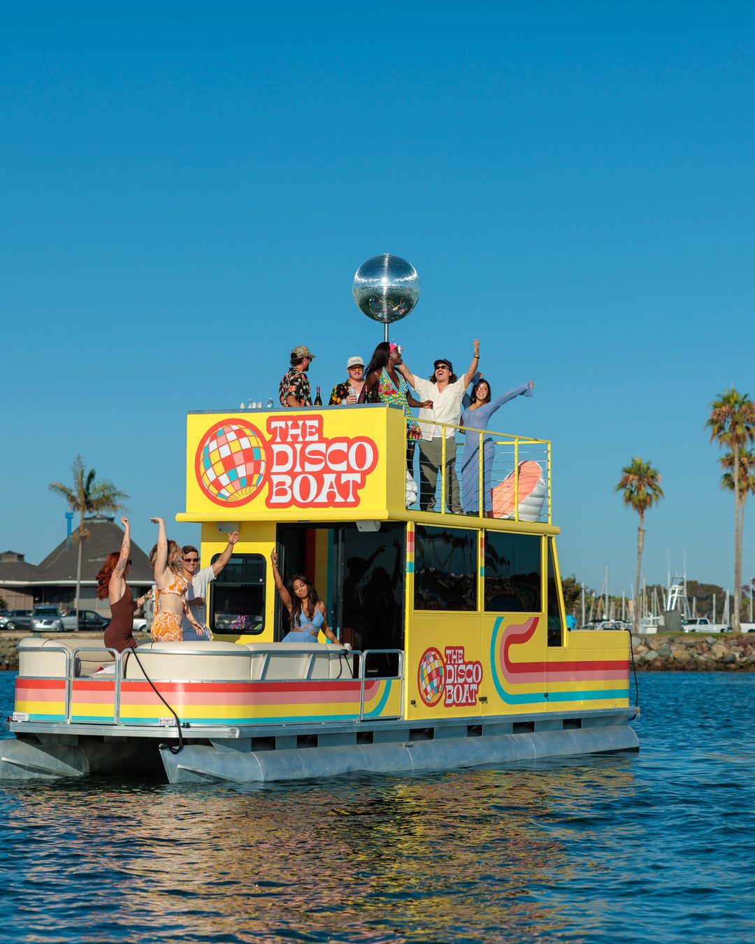 The Disco Boat on San Diego Bay — guests on the rooftop with palm trees behind