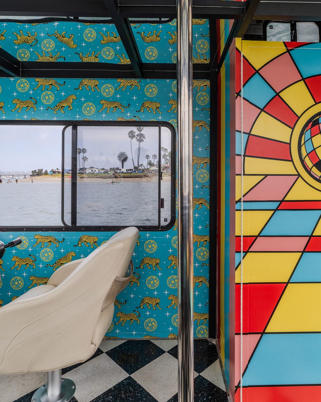 Disco Boat interior — leopard-print walls, retro-wrapped helm with psychedelic swirls, sunburst-and-disco-ball door mural